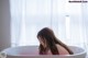 A woman sitting in a bathtub in front of a window.