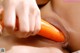 A woman is holding a carrot in her mouth.