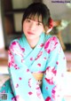 A woman in a blue and pink kimono sitting on a chair.