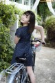 A woman in a polka dot dress standing next to a bike.