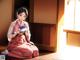 A woman in a pink kimono sitting on the floor holding a bowl.