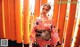 A woman in a kimono standing in front of a row of orange torii gates.