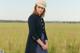 A woman standing in a field wearing a hat.