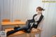 A woman sitting on top of a desk in a classroom.