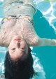 A woman floating in a pool with her head above the water.