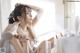 A woman sitting on a bed with a hair dryer in her hand.